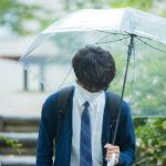 雨の中傘をさす高校生