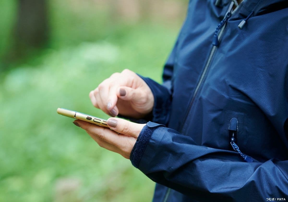 登山しながらスマホで地図を見る女性