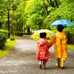 雨の中傘を指して歩く男の子と女の子
