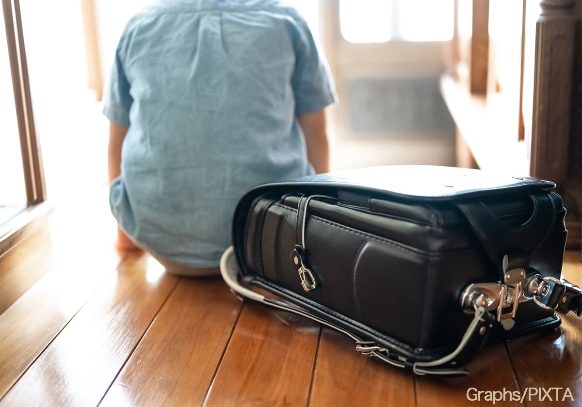 玄関で登校を渋る小学生の男の子のイメージ